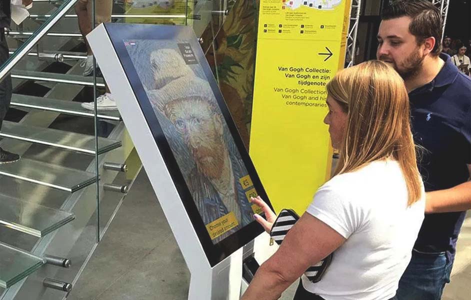 Visitors collecting tickets from the Van Gogh Museum counter or self-service kiosks