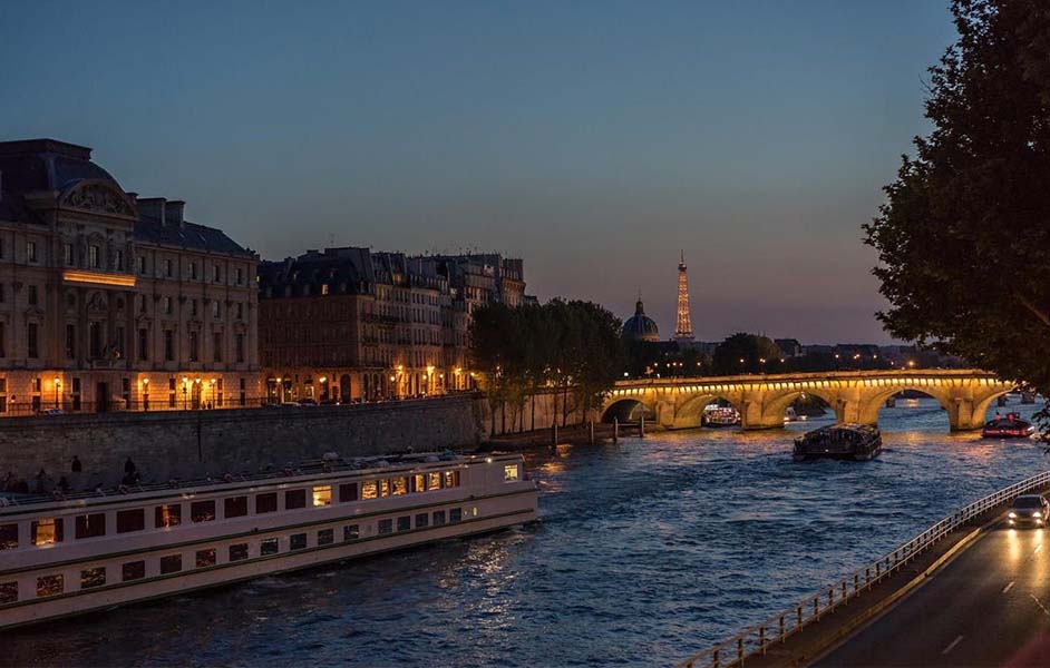 romantic things to do in paris - Couple enjoying a romantic evening Seine River cruise with Paris city lights